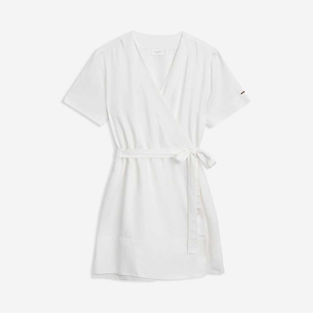 The Women's Cozy Earth Coastal Comfort Wrap Dress by Cozy Earth is a short, white wrap dress featuring short sleeves and a V-neckline. It is tied at the waist with a matching fabric belt and boasts a simple yet elegant design, making it ideal for casual or semi-formal occasions. The background is plain white. |Color:White