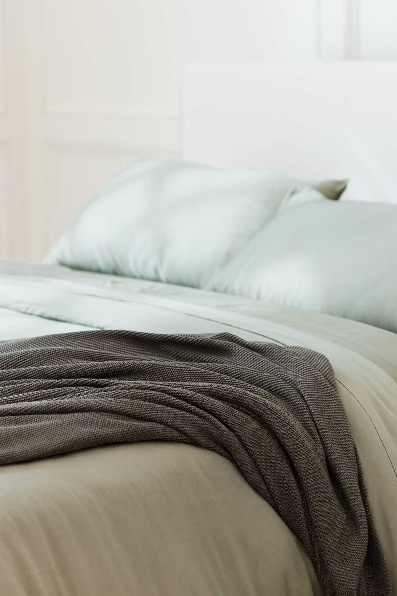 Charcoal cloud knit blanket sitting on bed |Color:Charcoal