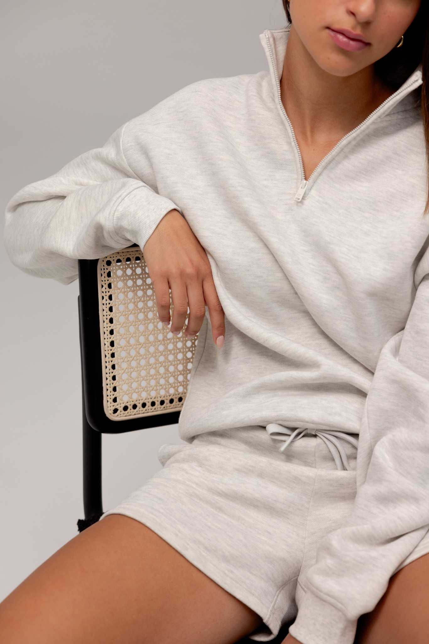 Heather Grey CityScape Quarter Zip. The quarter zip is being worn by a female model. The model is wearing accompanying CityScape clothing to complete the look of the quarter zip. The photo was taken with a grey background. |Color:Heather Grey