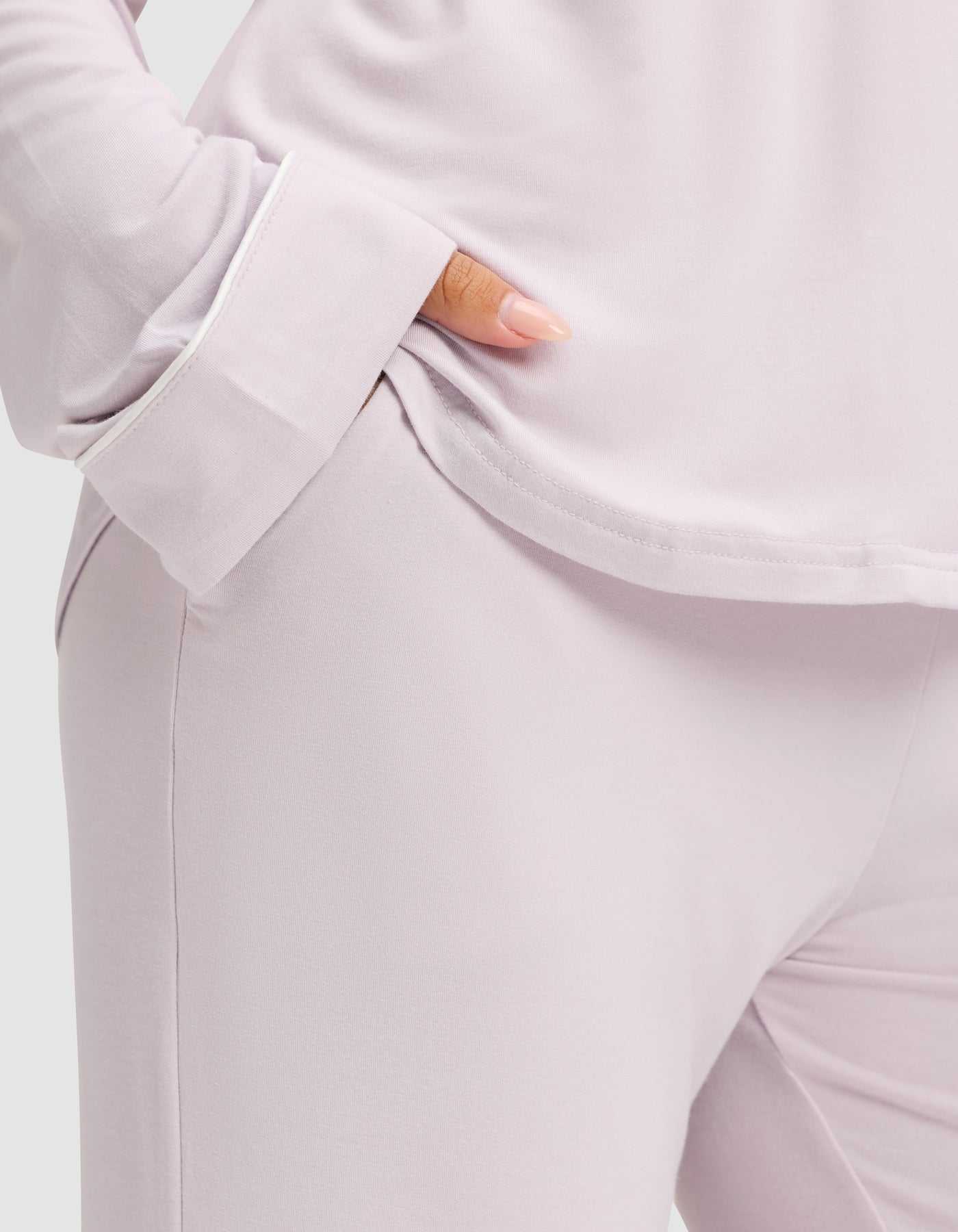 A person models the Cozy Earth Women's Bamboo Stretch-Knit Long Sleeve Pajama Set in light lavender, hand in pocket, with the torso and upper legs visible to showcase the soft, comfortable fabric. |Color:Lilac