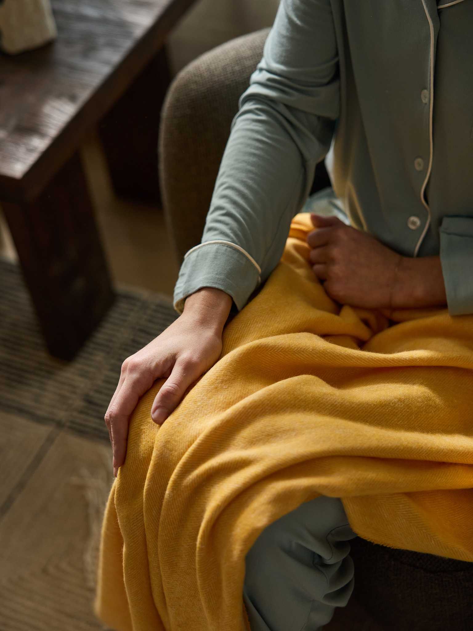 Close up of woman with sunflower herringbone tassel throw on her lap |Color:Sunflower