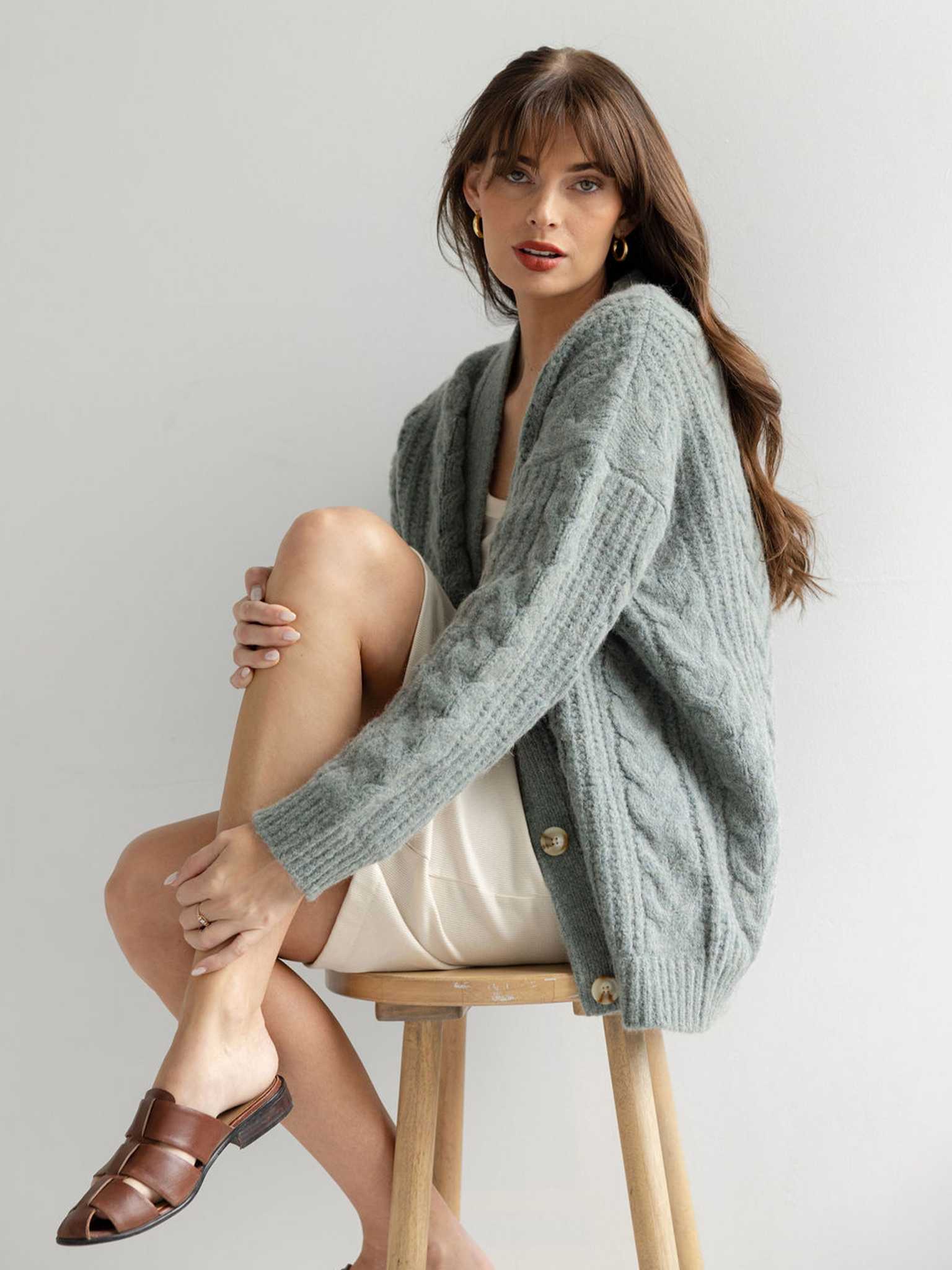 Woman sitting on wooden stool with her knee up wearing thyme cardigan |Color:Thyme