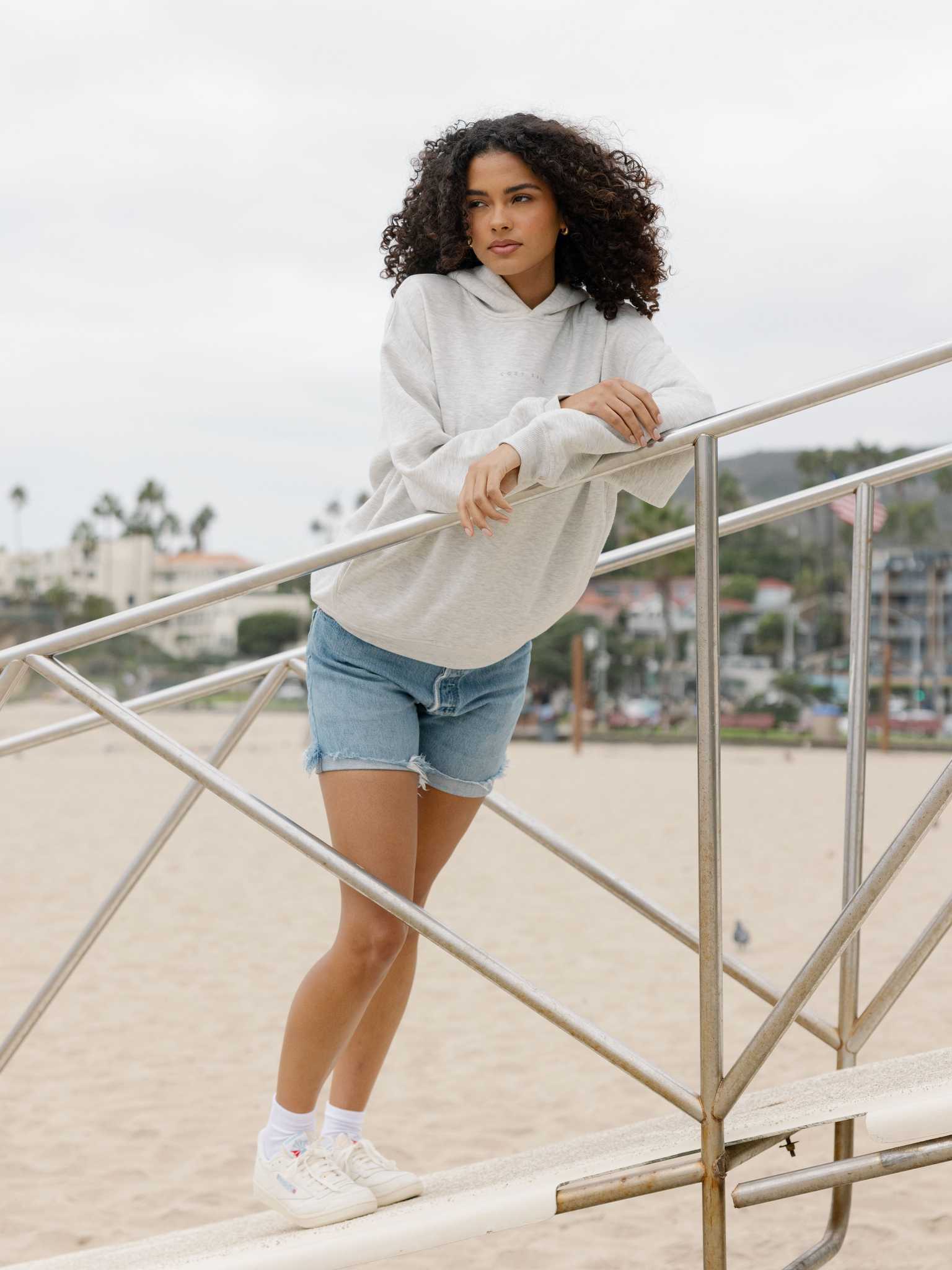 Heather GreyWoman wearing jorts and heather grey cityscape hoodie on the beach |Color:Heather Grey