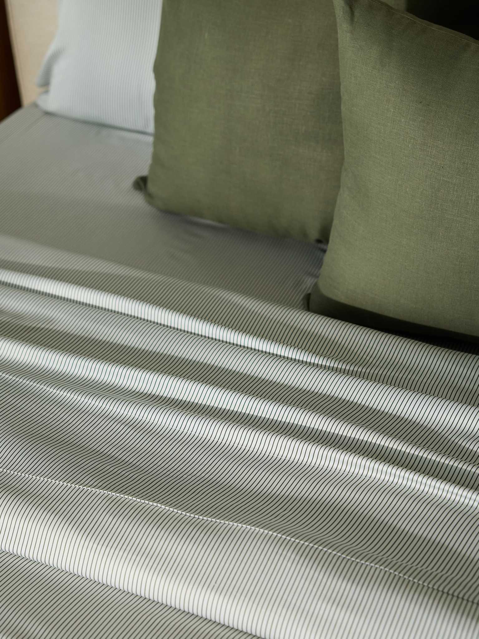 A neatly made bed featuring the Cozy Earth Bamboo Duvet Cover in shades of gray. Green square pillows are arranged on the bed, adding a touch of color. The smooth and polished fabric creates an inviting and cozy atmosphere. |Color:Jade Pinstripe
