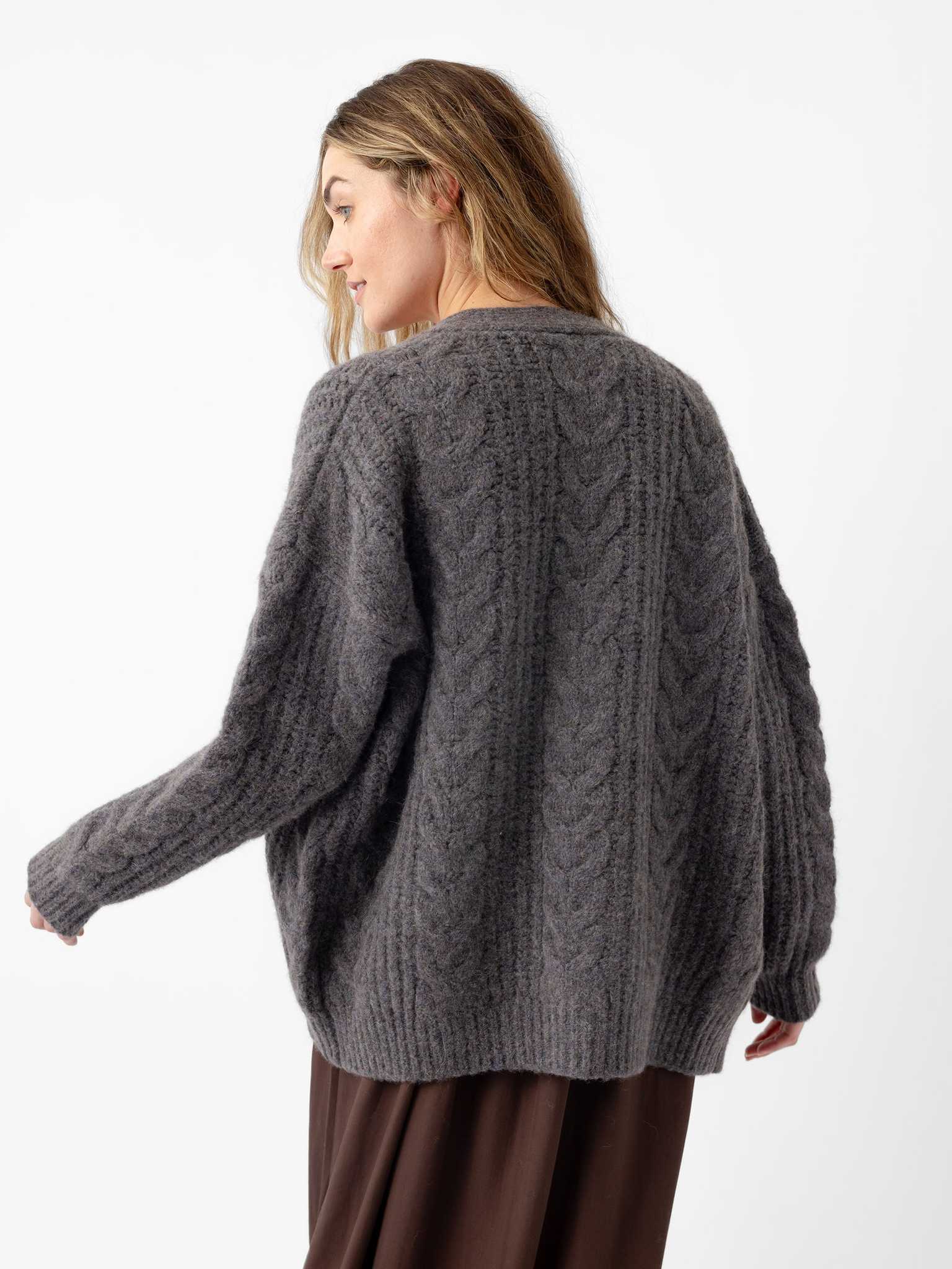 A woman with long hair is turned to the side, wearing a cozy gray oversized cable-knit cardigan from Cozy Earth and a brown skirt. The background is plain white. |Color:Thunder