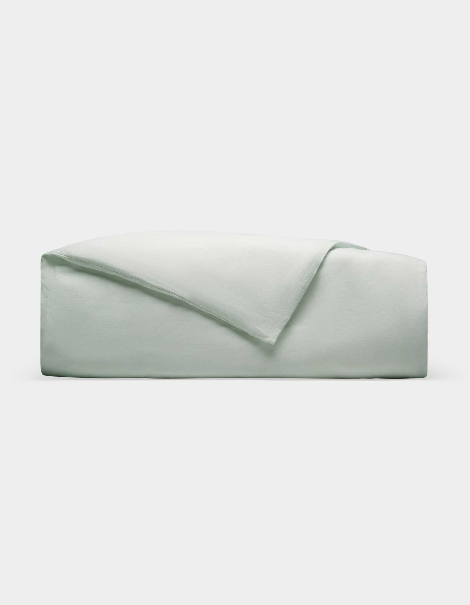 A Cozy Earth Linen Duvet Cover, neatly folded in light gray or pale green, is stacked on a plain white background.|Color:Mist