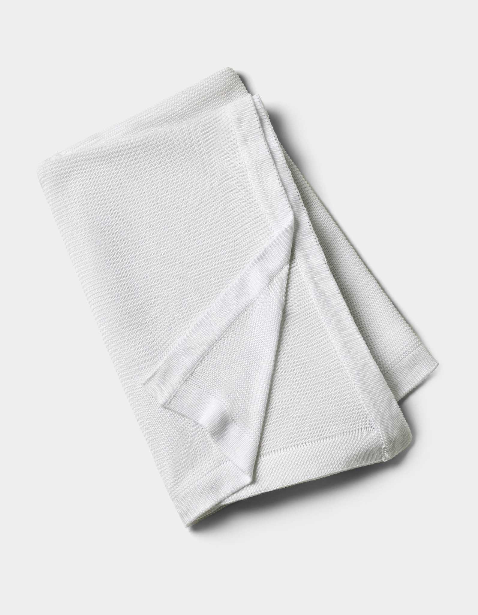 The Cozy Earth Cloud Knit Blanket by Cozy Earth is neatly folded and displayed on a plain, light background, showcasing its white textured fabric.|Color:White