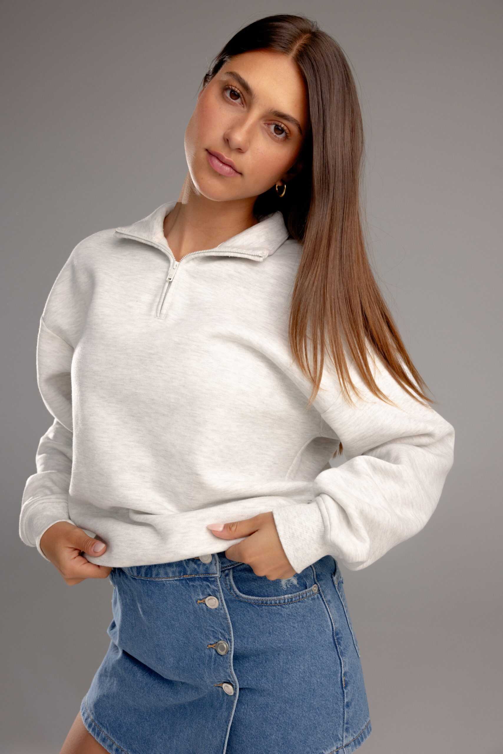 Heather Grey CityScape Quarter Zip. The quarter zip is being worn by a female model. The model is wearing an accompanying jean skirt to complete the look of the quarter zip. The photo was taken with a grey background. |Color:Heather Grey
