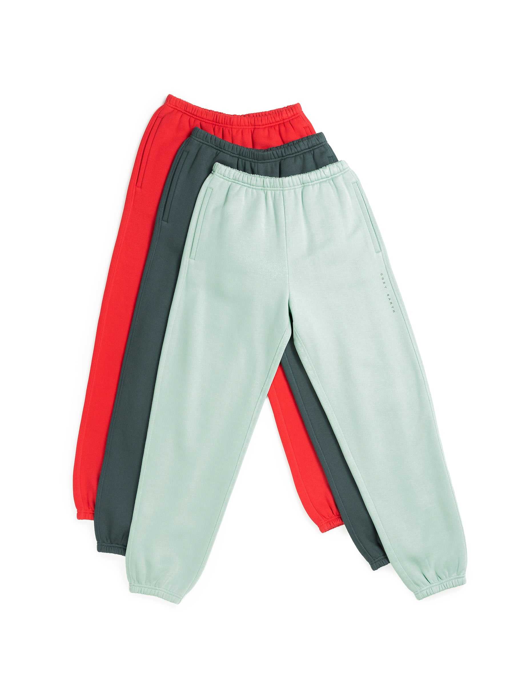 The Men's CityScape Sweatpant from Cozy Earth is showcased with three pairs overlapping each other. These sweatpants come in three distinct colors: red, dark green, and light mint green. They are designed with elasticated waistbands and ankle cuffs, set against a plain white background. |Color:Wintergreen
