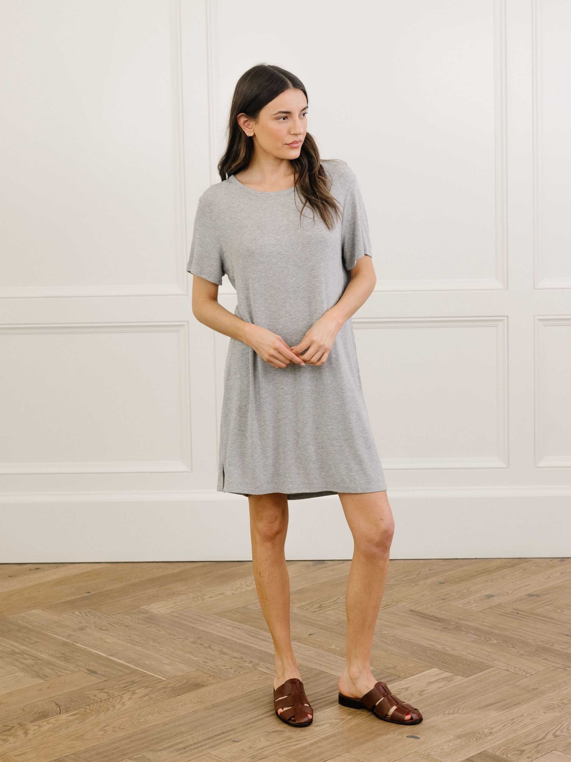 A woman standing in a grey Cozy Earth bamboo rib-knit boyfriend sleep dress with short sleeves, knee-length, in a lounge or bedroom setting. |Color:Grey
