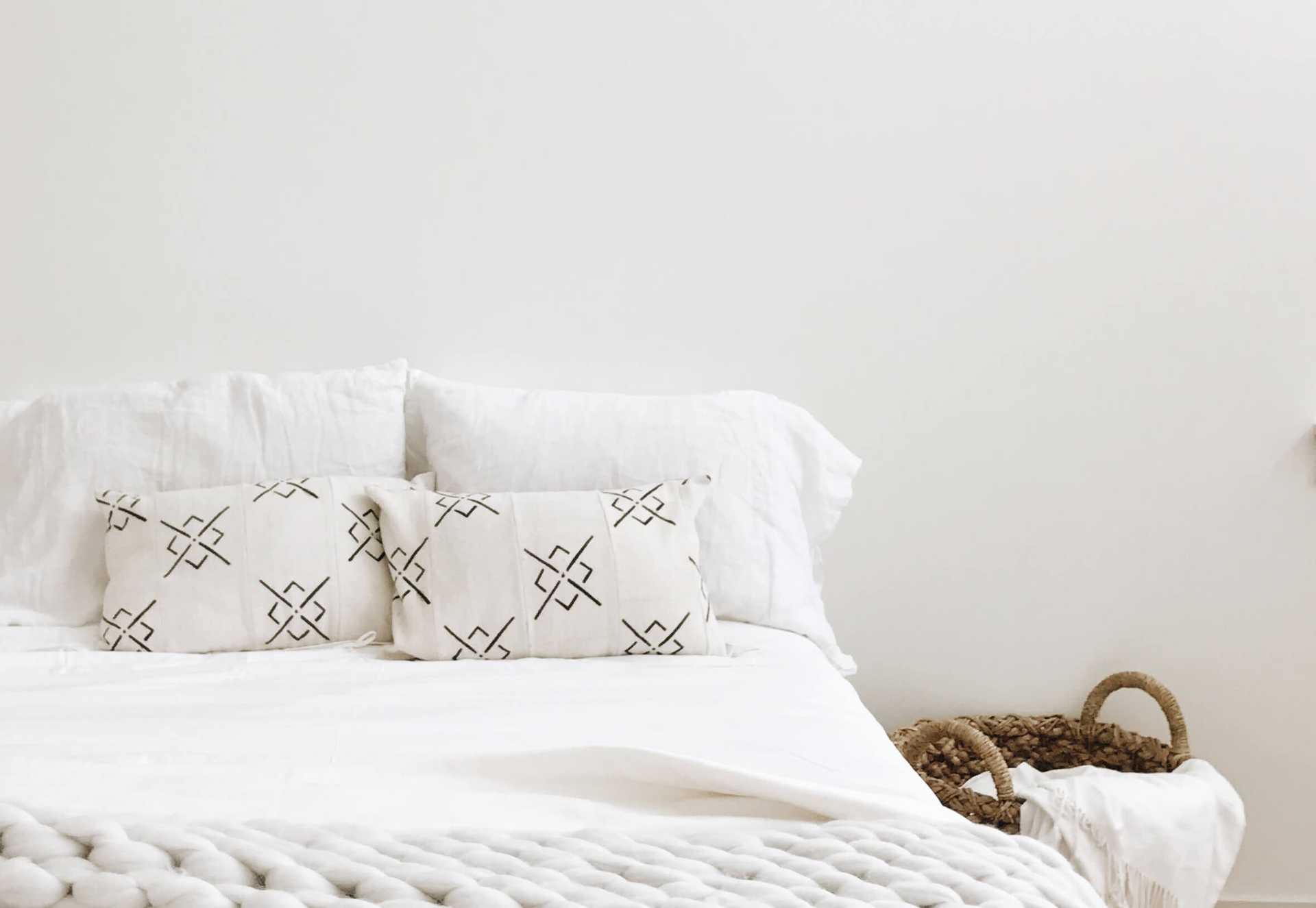 Bed with with bedding and a brown basket to the side |Color:White