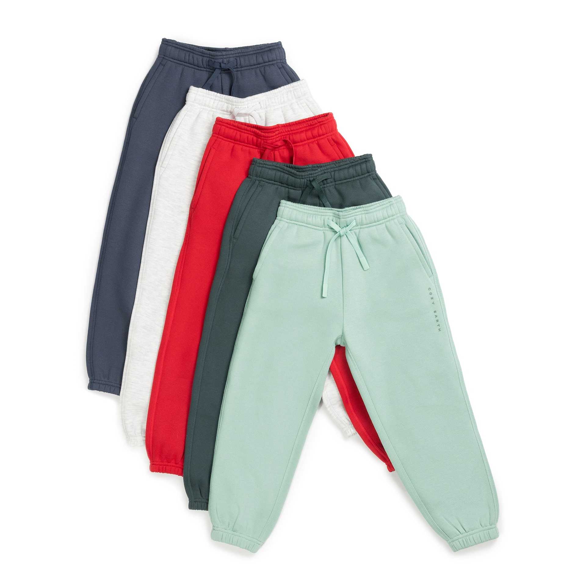 Five pairs of the Kid's CityScape Sweatpant from Cozy Earth in an array of colors—dark blue, light gray, red, dark green, and mint green—are arranged overlapping each other and fanned out side by side. |Color:Wintergreen