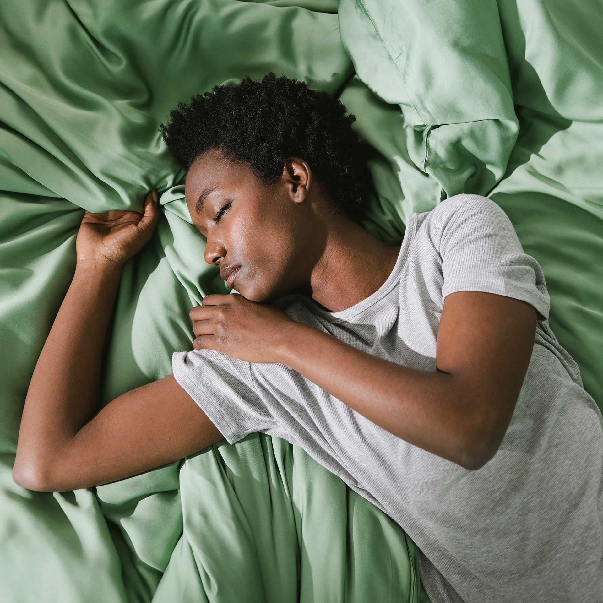 Fern Sheets on bed. A woman rests on the bed. |Color:Fern