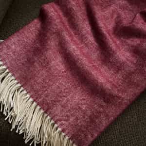 Berry herringbone tassel throw laying on sofa |Color:Berry