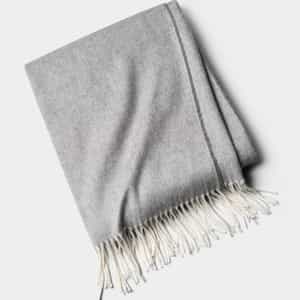 The Cozy Earth Bamboo Herringbone Tassel Throw is a folded light gray blanket with white fringed tassels on one edge, shown against a plain white background.|Color:Cloud