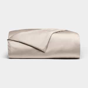 The Bamboo Duvet Cover by Cozy Earth is shown neatly folded in light beige with a smooth, shiny finish against a white background; one corner is flipped open to reveal the inner side.|Color:Driftwood