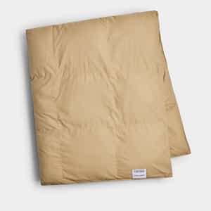 The Cozy Earth Down Alternative Throw is a neatly folded, light brown quilted blanket featuring a small white tag in one corner, displayed on a plain white background.|Color:Sandalwood
