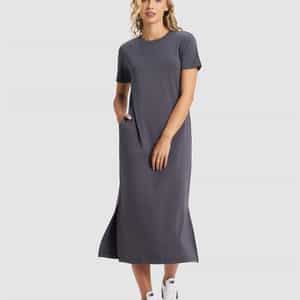 A woman smiles against a plain background, wearing the Cozy Earth Women's Brushed Bamboo Midi Dress in gray with short sleeves, side pockets, and white sneakers. She has one hand in her pocket.|Color:Graphite