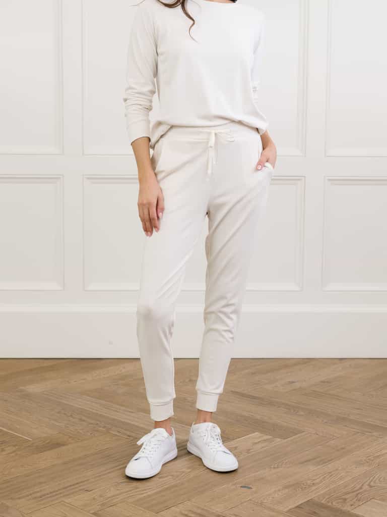 Ivory Bamboo Jogger Set modeled by a woman. The photo was taken in a high contrast setting, showing off the colors and lines of the pajamas. |Color: Ivory