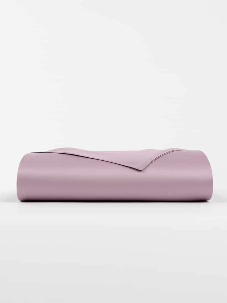 The Bamboo Flat Sheet by Cozy Earth is folded neatly on a white background, showcasing a smooth and clean light purple appearance. |Color:Lavender