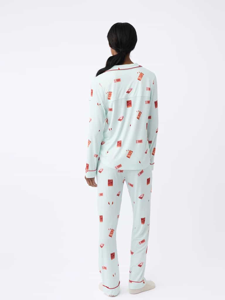 A person with long hair faces away, wearing the Cozy Earth Last Chance Women's Bamboo Stretch-Knit Long Sleeve Pajama Set in light blue with a red takeout box design against a plain white background. |Color:Perfect Match