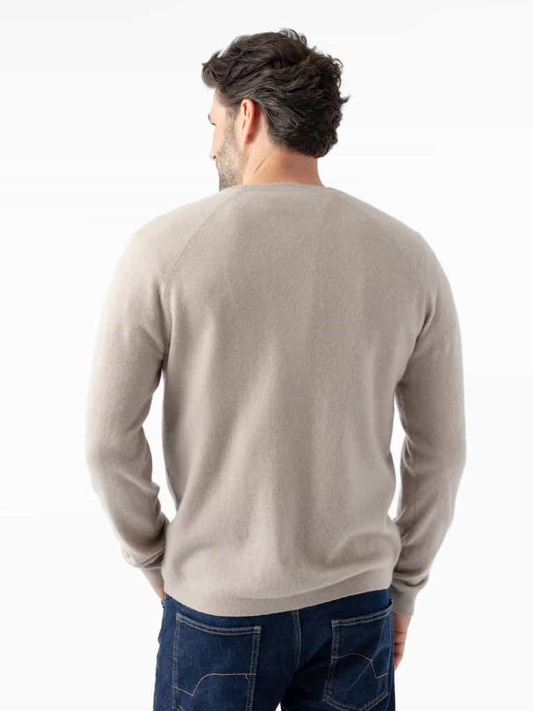 A man with short dark hair is facing away from the camera. He is wearing a Men's Crewneck Sweater in light beige by Cozy Earth and dark blue jeans. The background is white and uncluttered. |Color:Sandstone