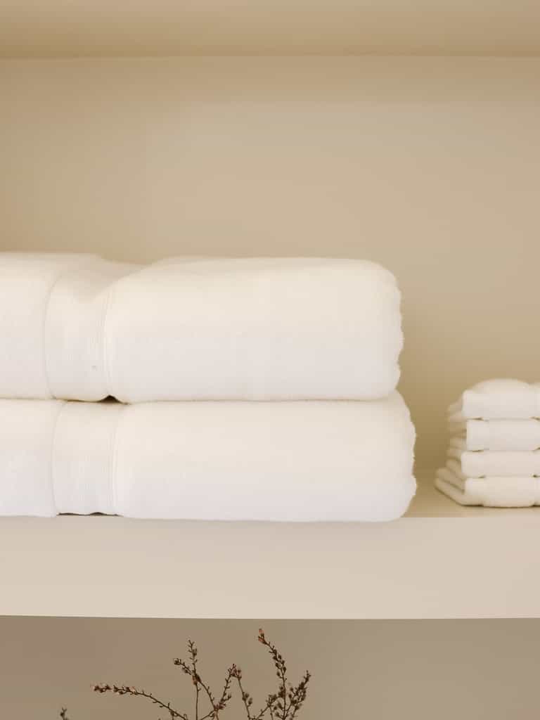 White luxe bath towels and washcloths folded on shelf |Color:White