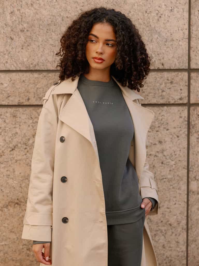 Storm CityScape Pullover Crew. The Pullover is being worn by a female model. Accompanying city scape clothing is being worn to complete the look of the outfit. The photo was taken with a city building background. |Color:Storm