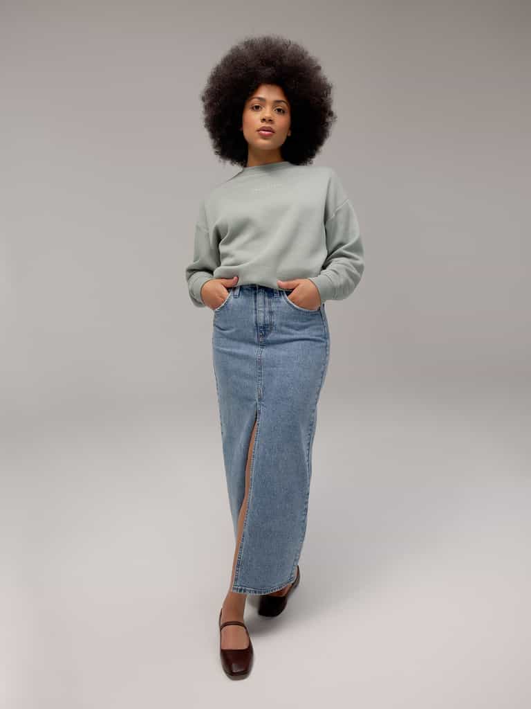 Haze CityScape Pullover Crew. The Pullover is being worn by a female model. An accompanying jean skirt is being worn to complete the look of the outfit. The photo was taken with a white background. |Color:Haze