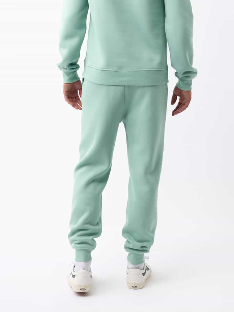 Rear view of a person wearing the Men's CityScape Jogger in light green from Cozy Earth and white sneakers against a white background. |Color:Wintergreen