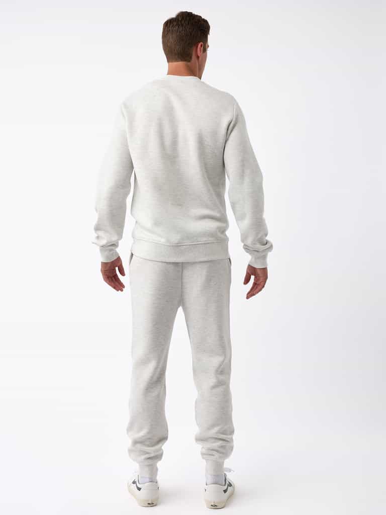 A person is wearing the Men's CityScape Jogger from Cozy Earth in a light gray color, paired with white sneakers, and is facing away from the camera against a plain white background. |Color:Heather Grey