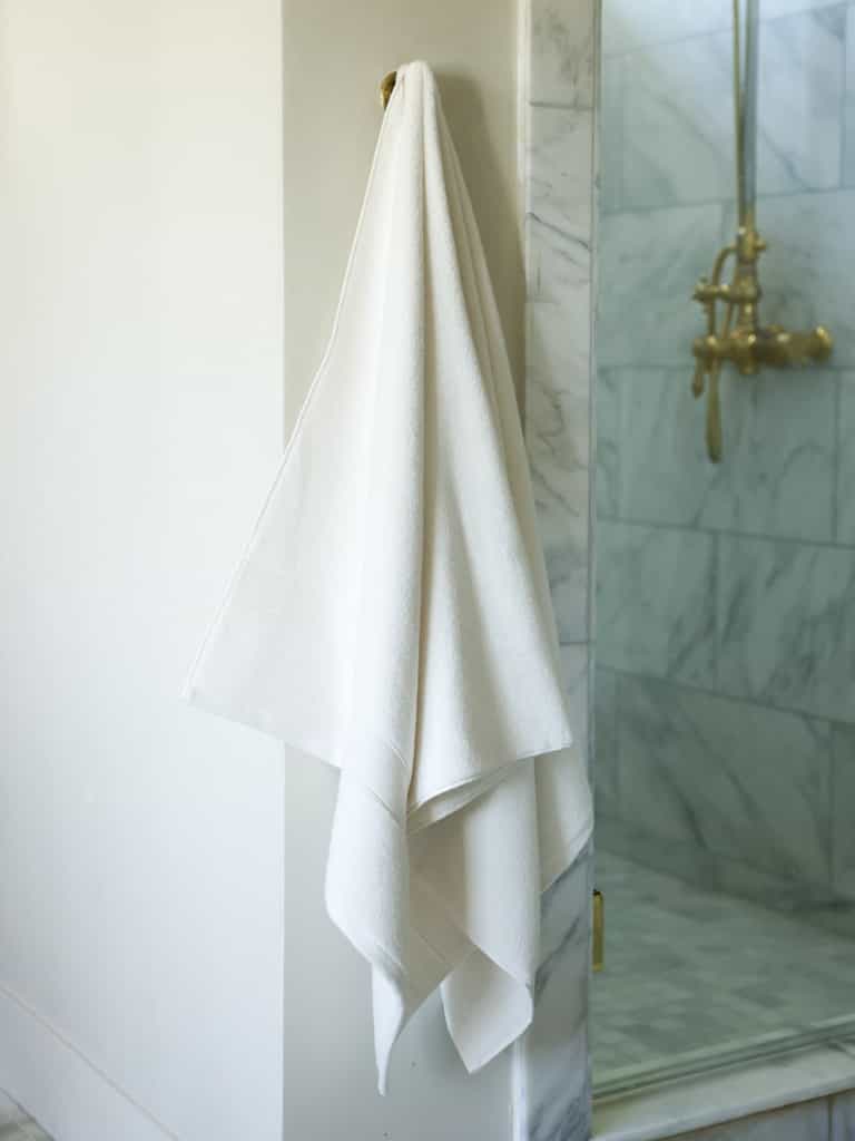 Seashell luxe bath sheet hanging next to shower |Color:Seashell
