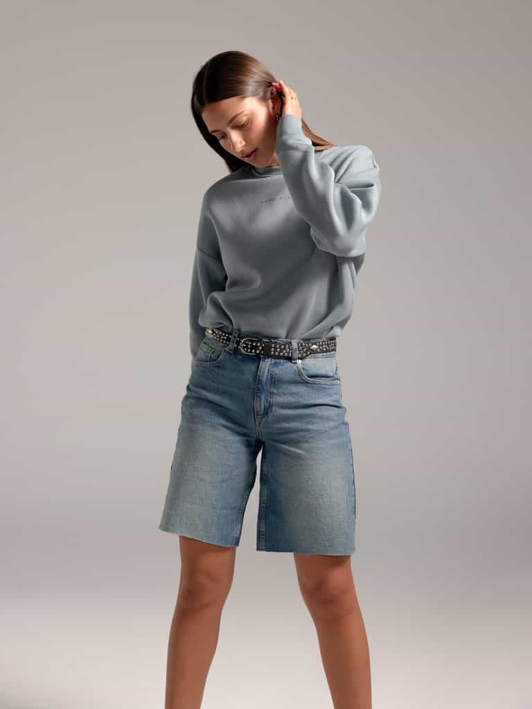 Woman wearing Smokey Blue CityScape Crewneck with grey background |Color: Smokey Blue