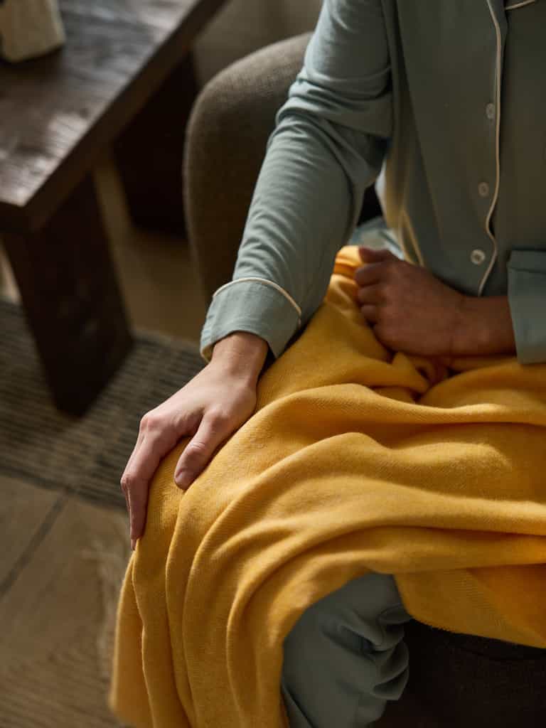 Close up of woman with sunflower herringbone tassel throw on her lap |Color:Sunflower