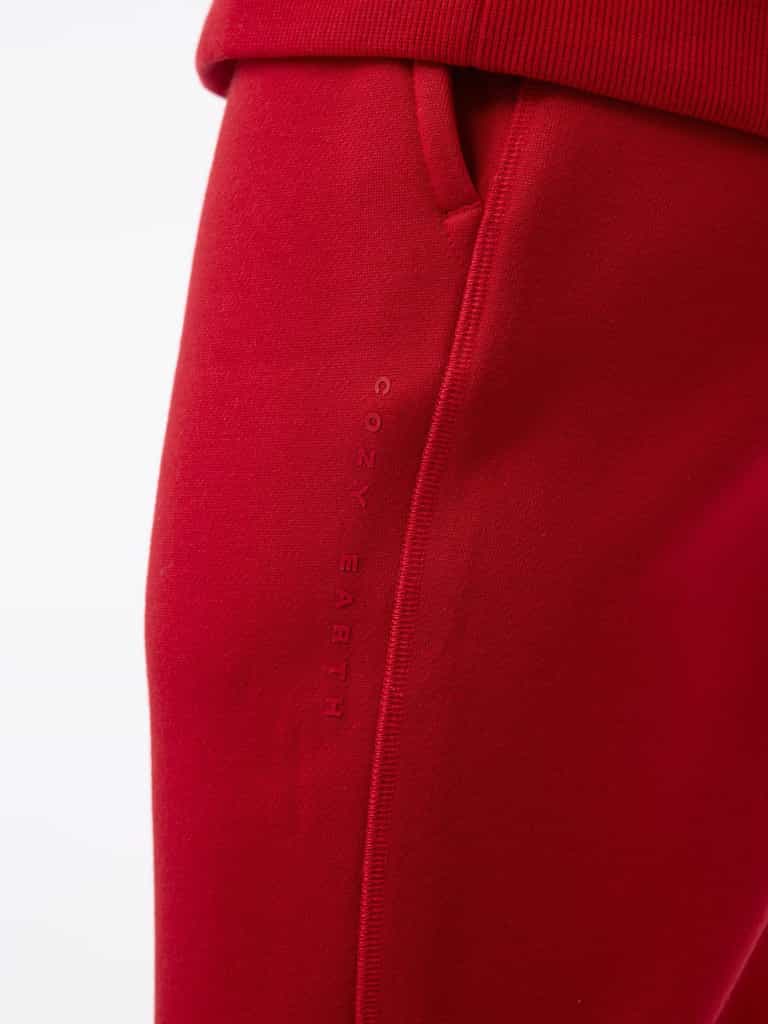 Close-up of the Men's CityScape Jogger in red, featuring a side pocket with "Cozy Earth" embroidered vertically. The texture appears soft and smooth, highlighting the comfortable fabric. The focus is on the stitching and fabric detail. |Color:Crimson