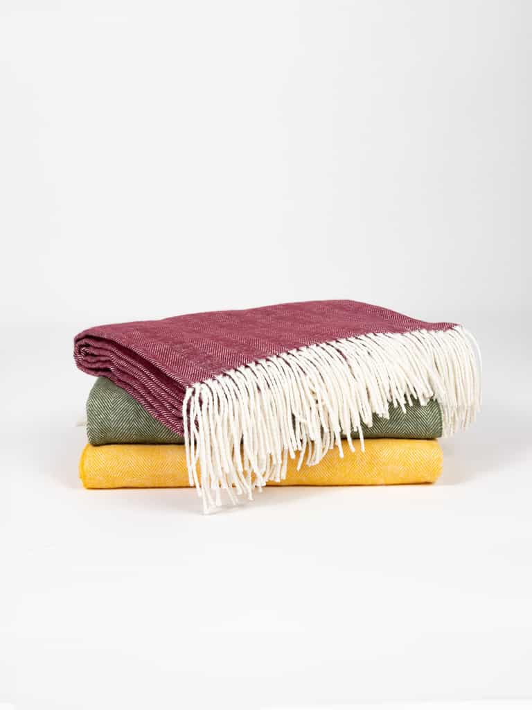 Three colors of herringbone tassel throws folded with white background |Color:Berry