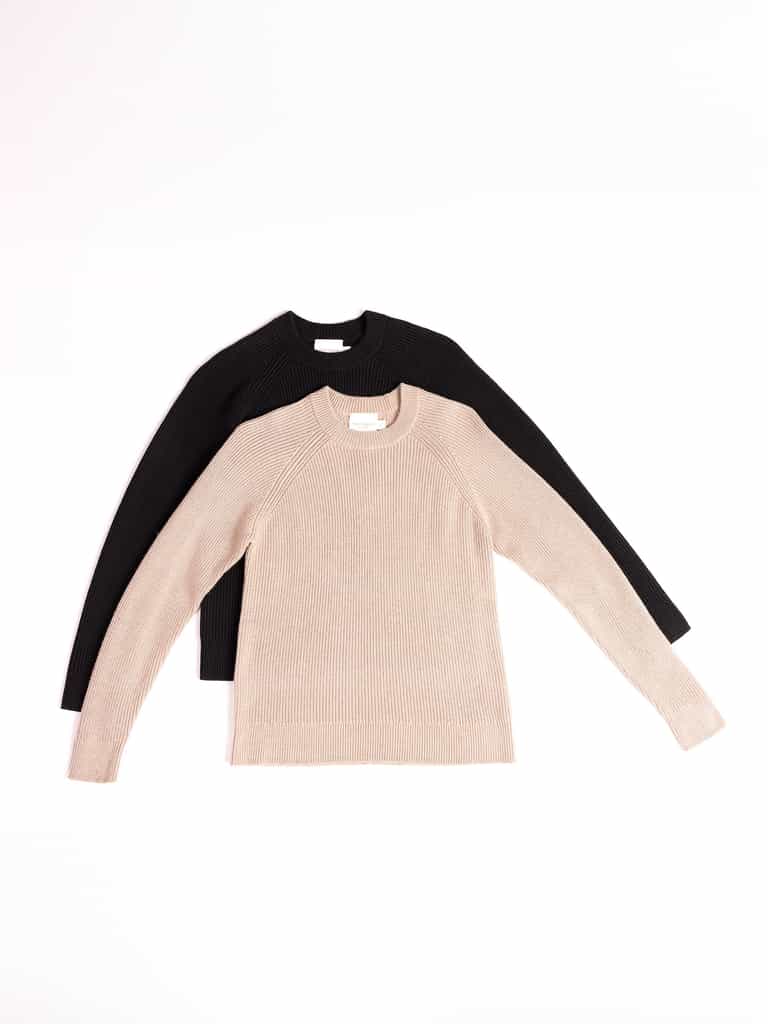 Two Cozy Earth Women's Classic Crewneck sweaters are laid flat next to each other. The front sweater is beige with a ribbed texture, while the back sweater is black. Both have crew necklines and appear to be made of a comfortable, knitted material. The background is plain white. |Color:Jet Black