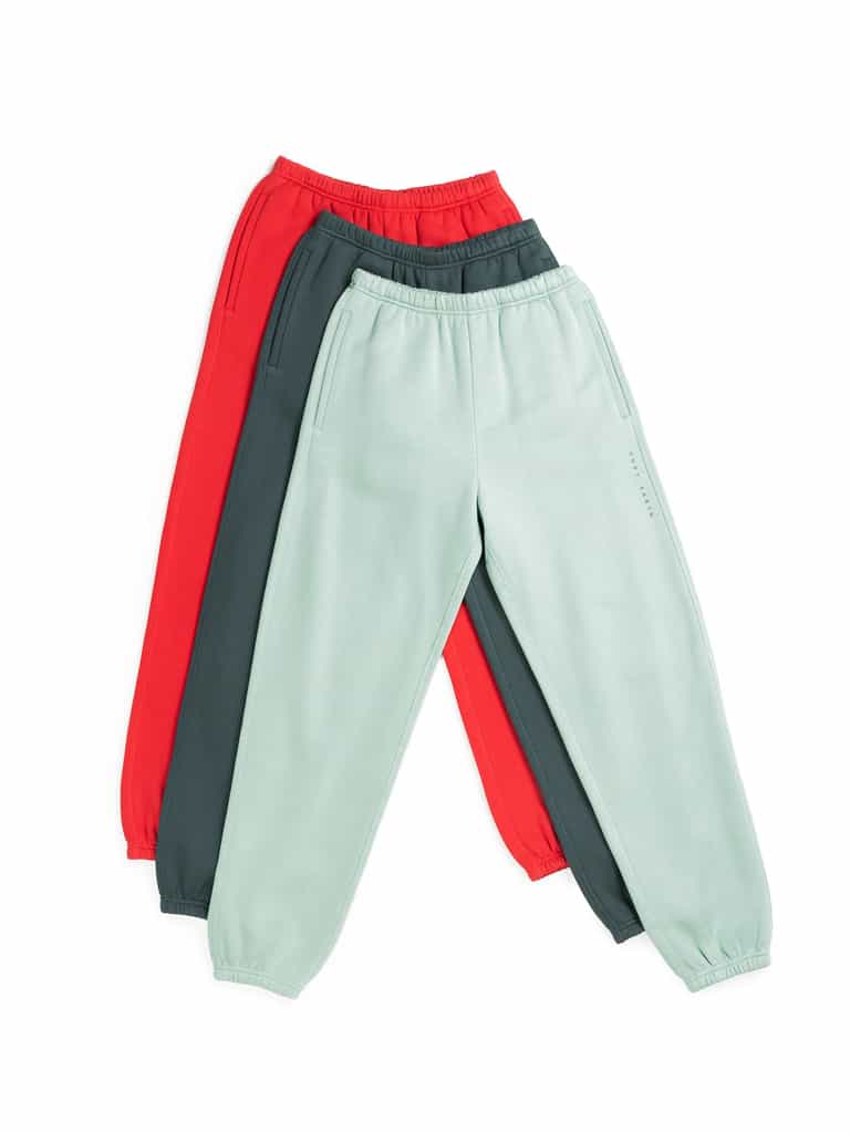 The Men's CityScape Sweatpant from Cozy Earth is showcased with three pairs overlapping each other. These sweatpants come in three distinct colors: red, dark green, and light mint green. They are designed with elasticated waistbands and ankle cuffs, set against a plain white background. |Color:Wintergreen