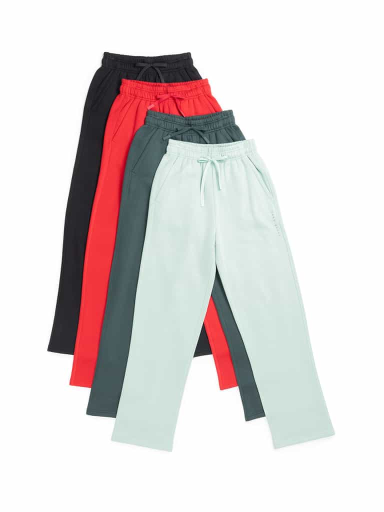 Four pairs of the Women's CityScape Wide Leg Pant by Cozy Earth are laid out in a fanned arrangement. From top to bottom, the colors are black, red, dark green, and light mint green. Each pair features an elastic waistband and drawstrings. |Color:Wintergreen
