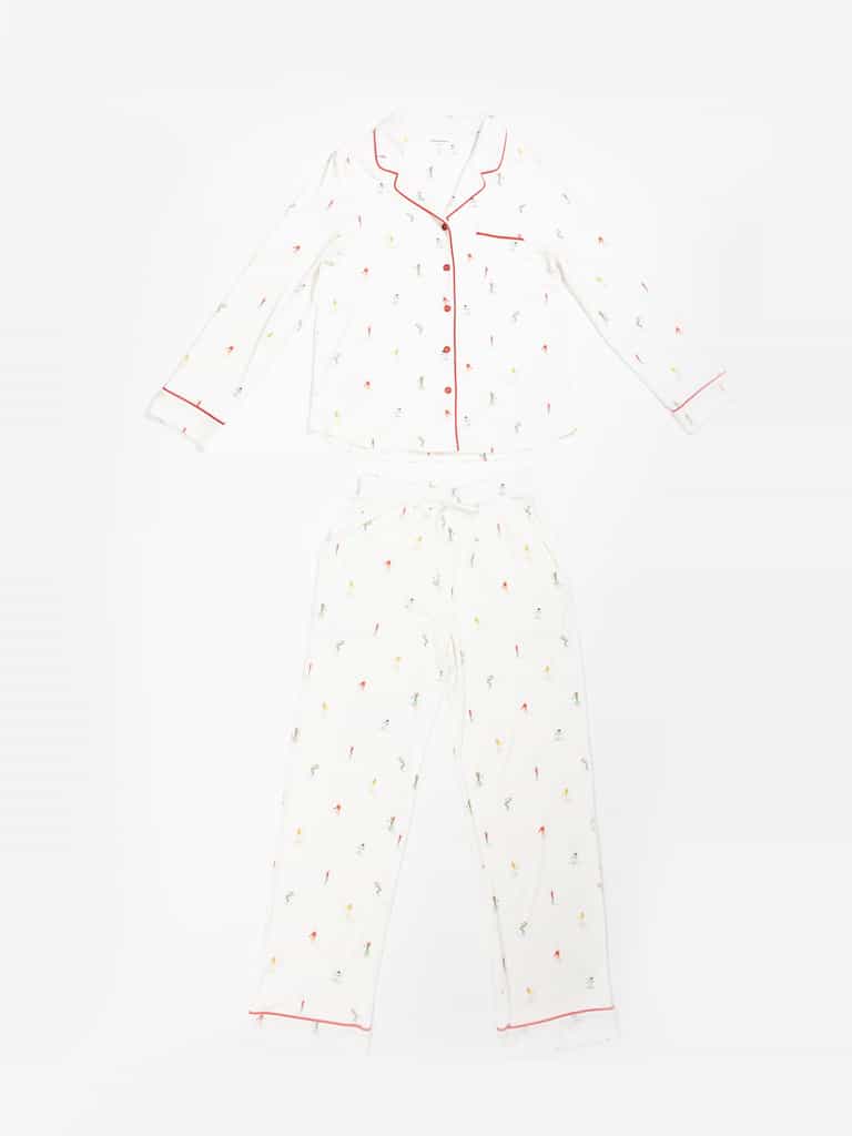 The Cozy Earth Last Chance Women's Bamboo Stretch-Knit Long Sleeve Pajama Set features a white top and bottoms with multicolored beach prints, red piping on the collar, cuffs, and pocket of the top, and pants with a drawstring waist and red piping at the cuffs. |Color:Skiers Ivory