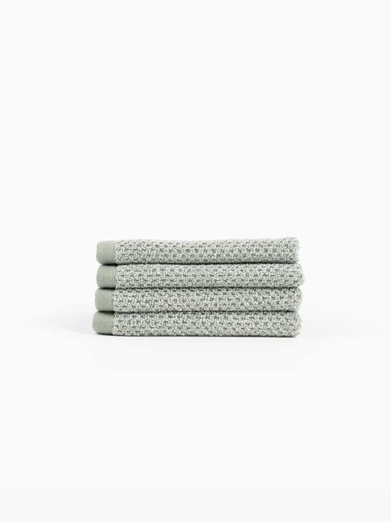 A neatly folded stack of four Cozy Earth Nantucket Bath Towels in textured light gray rests on a white background.|Color:Heathered Sage