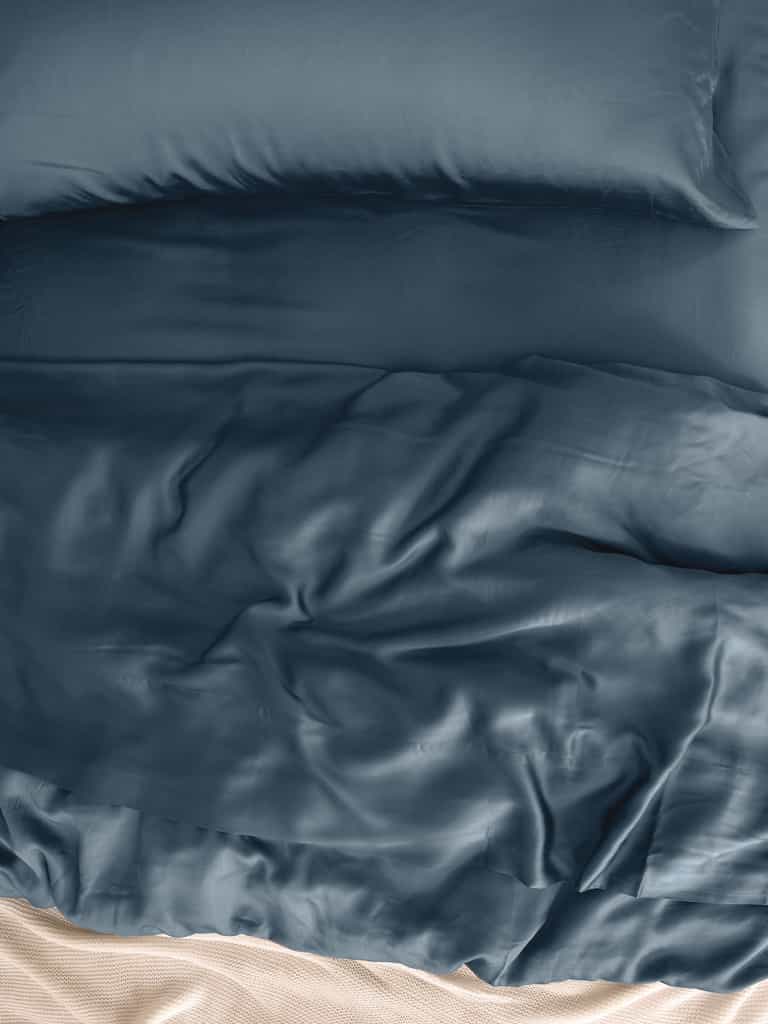 Close up of pacific blue bedding on an unmade bed |Color:Pacific Blue