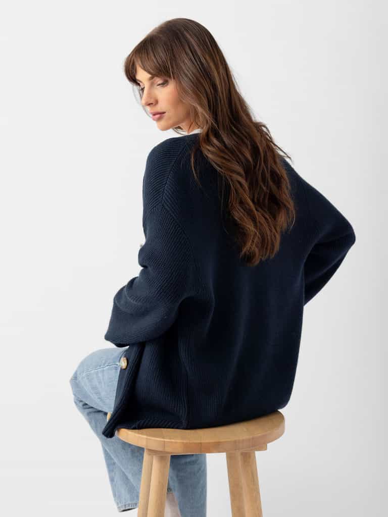 Back of woman in eclipse cardigan sitting on wooden stool |Color:Eclipse