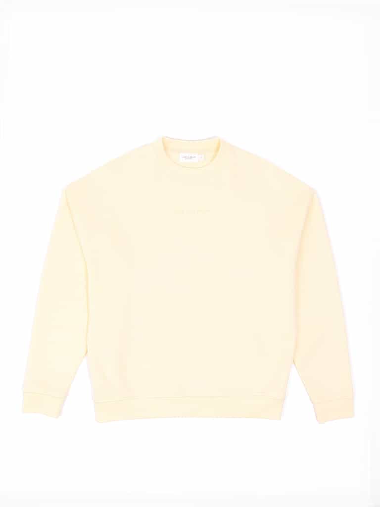 The Women's CityScape Crewneck by Cozy Earth is a light yellow sweatshirt with long sleeves, pictured flat against a white background with a small tag visible at the neckline. |Color:Lemonade