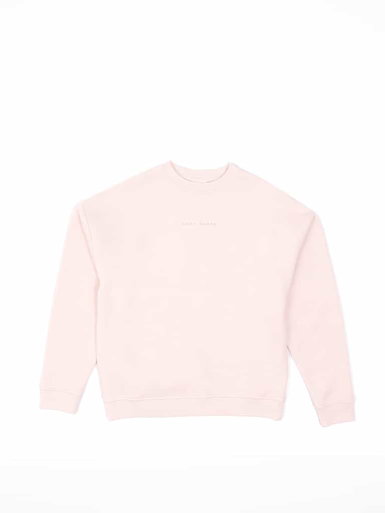 The Women's CityScape Crewneck by Cozy Earth is showcased on a white backdrop. This light pink sweatshirt has a crew neckline and subtle chest text that blends softly with the fabric, making it hard to read. |Color:Peony