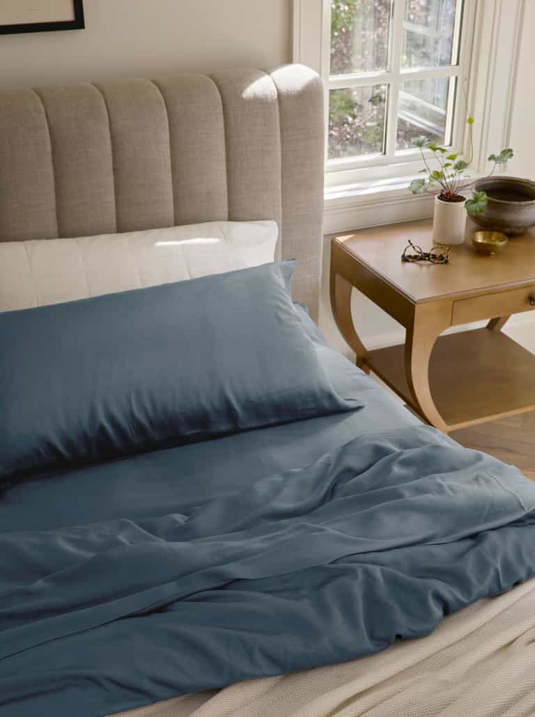 Pacific Blue bedding on an unmade bed with glasses on the nightstand |Color:Pacific Blue