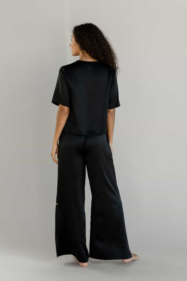 Black Serenity Silk Scoop Neck Tee modeled by a woman. The photo was taken in a high contrast setting, showing off the colors and lines of the tee. |Color: Black