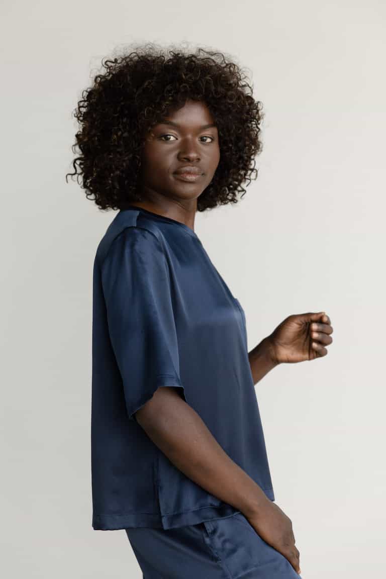 Navy Serenity Silk Scoop Neck Tee modeled by a woman. The photo was taken in a high contrast setting, showing off the colors and lines of the tee. |Color: Navy