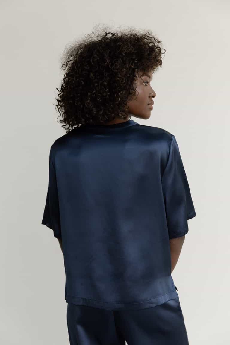 Navy Serenity Silk Scoop Neck Tee modeled by a woman. The photo was taken in a high contrast setting, showing off the colors and lines of the tee. |Color: Navy