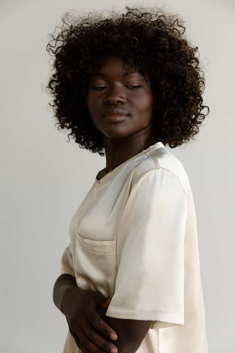 Champagne Serenity Silk Scoop Neck Tee modeled by a woman. The photo was taken in a high contrast setting, showing off the colors and lines of the tee. |Color: Champagne